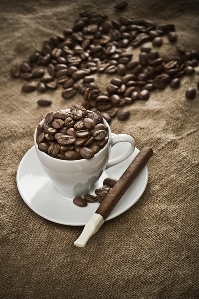 Cup with coffee beans and cigar on burlap — Stock Photo, Image