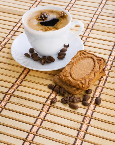 Чашка капучино с кофейными зёрнами и печеньем на коврике — стоковое фото