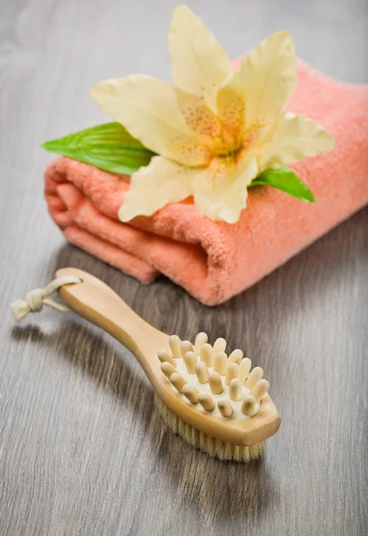 Flower on pink towel with massager and brush — Stock Photo, Image