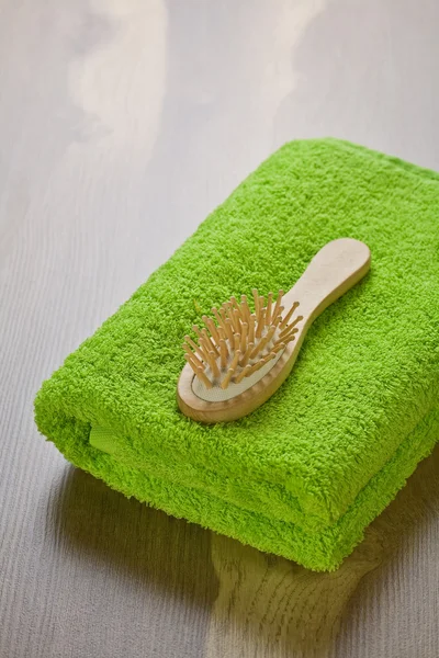 Asciugamano verde con spazzola per capelli — Foto Stock