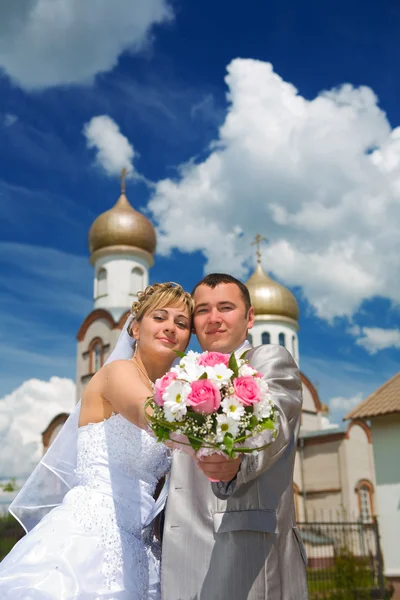 Nygift par på en bakgrund av en kyrka — Stock fotografie