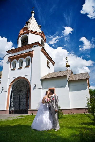 Новобрачный поцелуй на фоне церкви — стоковое фото