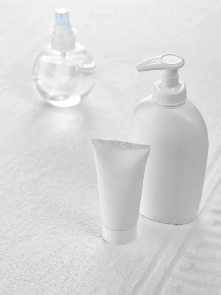 Tubo e bottiglie su asciugamano bianco — Foto Stock