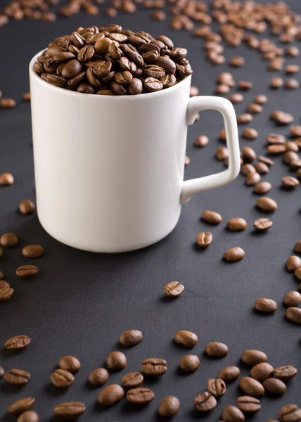 Weißer Kaffeebecher mit Kaffeekörnern auf schwarzem Hintergrund mit — Stockfoto