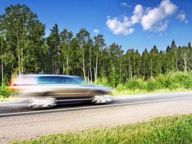 Car speeding on country highway, natural motion blur clipart