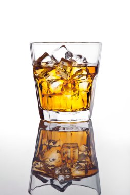 Glass of scotch whiskey and ice on glass table clipart