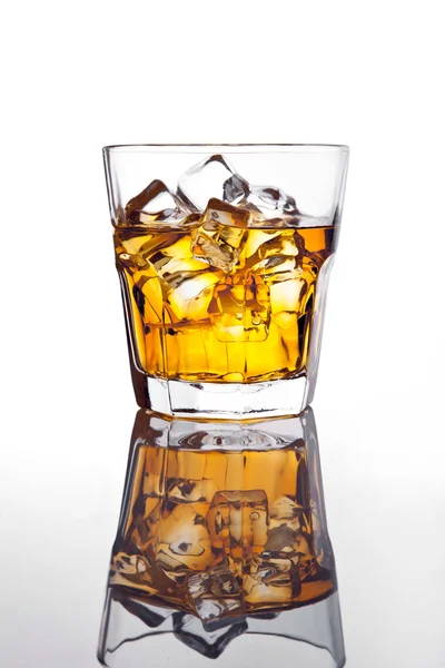 Glass of scotch whiskey and ice on glass table — Stock Photo, Image