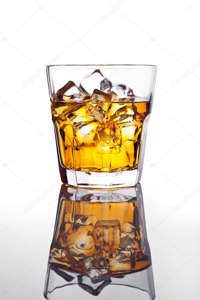 Glass of scotch whiskey and ice on glass table