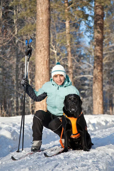 Женщина с собакой на прогулке в зимнем лесу — стоковое фото