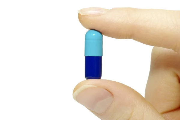Dedo segura pílula — Fotografia de Stock