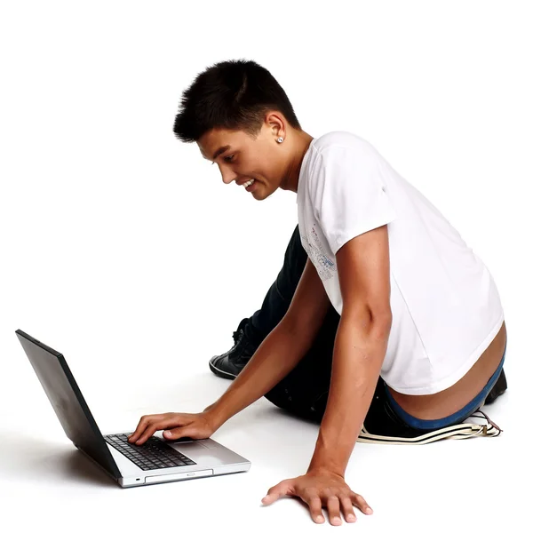 Fundersam ung man sitter på golvet med laptop, isolerad på whi — Stockfoto