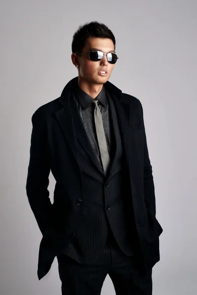 Atractivo joven vestido con elegante traje negro y gafas de sol —  Fotos de Stock
