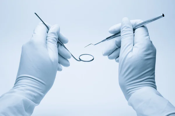 Τα χέρια του οδοντιάτρου που κατέχουν τα εργαλεία του κατά τη διάρκεια της εξετάσεως ασθενών — Φωτογραφία Αρχείου