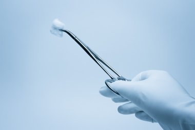 Hand of surgeon with forceps during surgery clipart