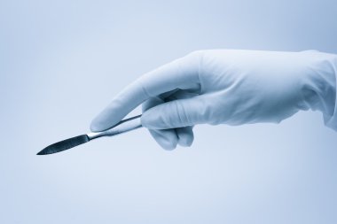 Hand of surgeon with scalpel during surgery clipart