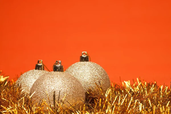 Guld glänsande julgranskulor med glitter över orange bakgrund — Stockfoto