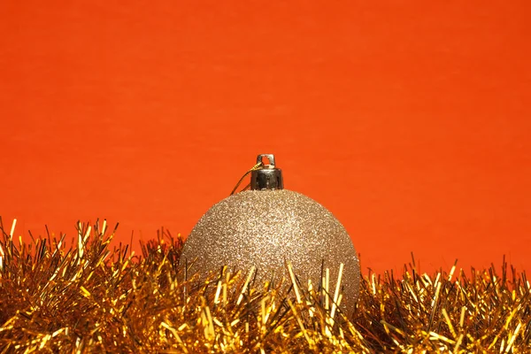 Glanzende Kerstmis bal met klatergoud over oranje achtergrond — Stockfoto
