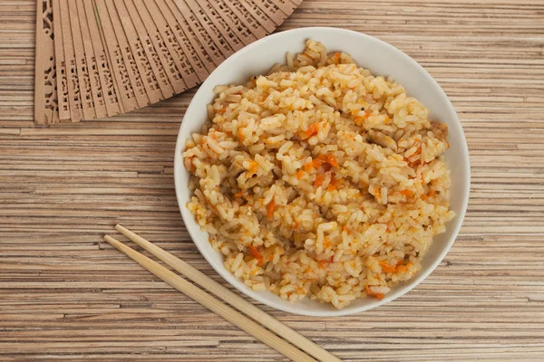 stock image Bowl of cooked rice with chopsticks and fan