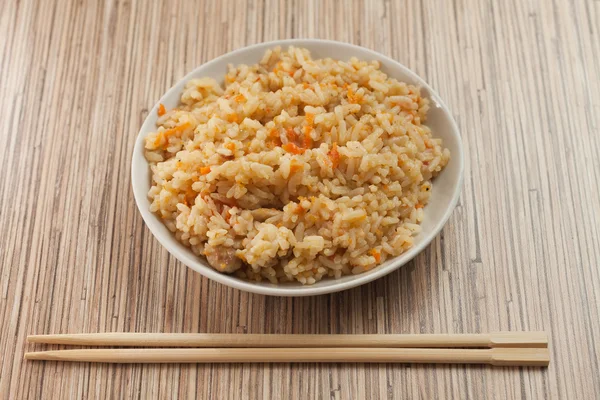 stock image Bowl of cooked rice with chopsticks on the bamboo textured table