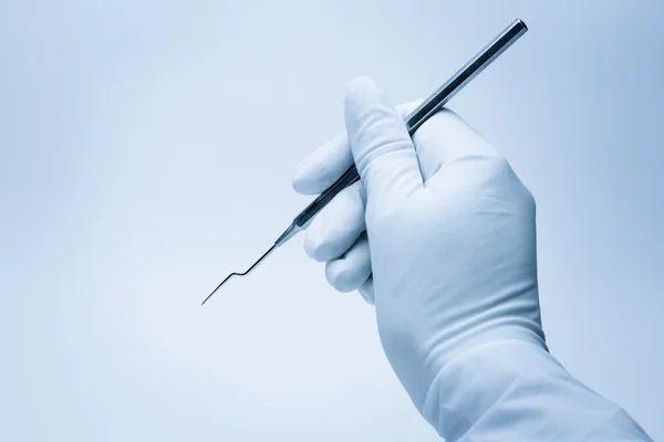 Mão do dentista segurando sua ferramenta durante o exame do paciente — Fotografia de Stock