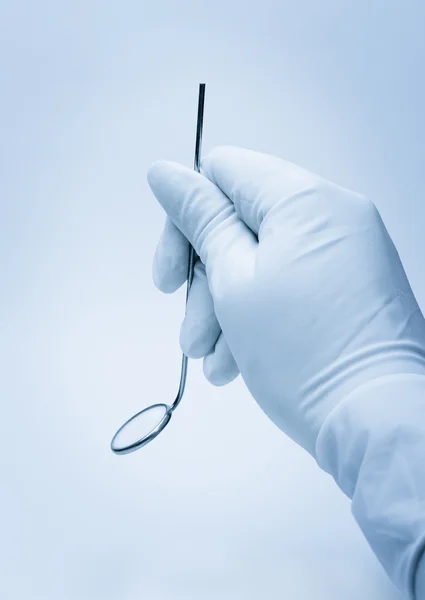 Χέρι του οδοντιάτρου που κατέχουν καθρέφτη κατά τη διάρκεια της εξετάσεως ασθενών — Φωτογραφία Αρχείου