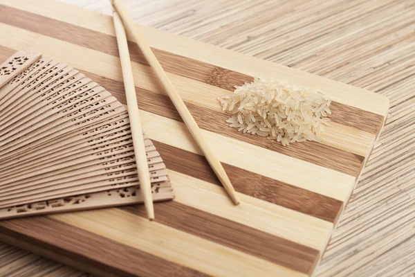 Ruwe rijst op het breadboard met stokjes — Stockfoto