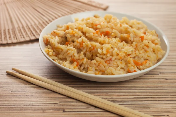 stock image Bowl of tasty cooked rice with chopsticks and fan