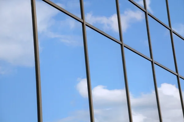 stock image Reflection of white clouds and blue sky in the windows of the modern building