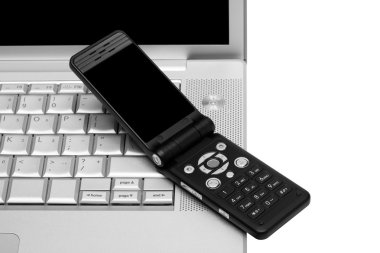 Mobile phone on the keyboard of a laptop clipart