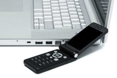 Mobile phone on the keyboard of a laptop clipart