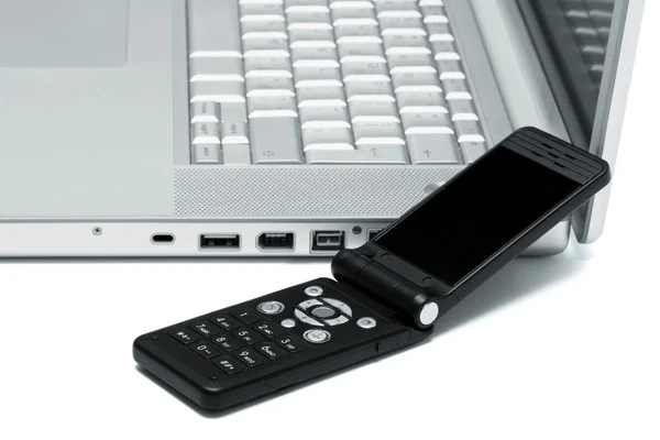 一台笔记本电脑的键盘上的移动电话 — 图库照片