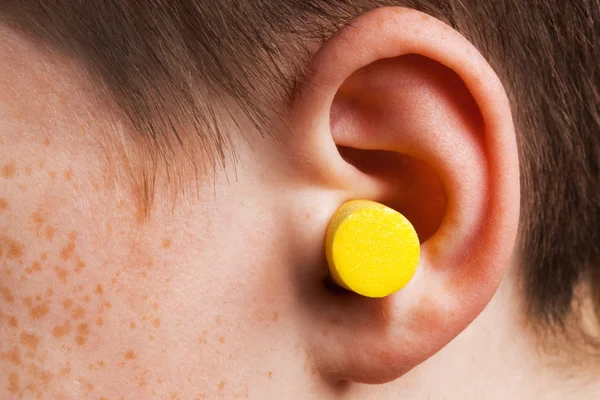 stock image Yellow earplug into the ear close up