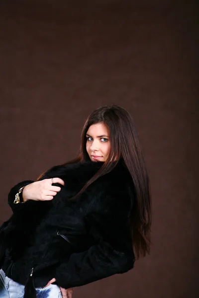 毛皮のコートと茶色の背景にジーンズで Attracive 若い女性 — ストック写真