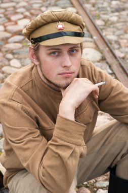 Soldier in uniform of World War I, sit down, resting on the pavement and smoking. Costume accord the times of World War I. Photo made at cinema city Cinevilla i clipart