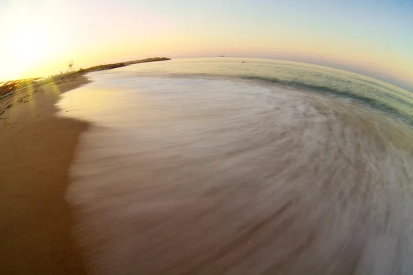 Восход солнца с волной на пляже — стоковое фото