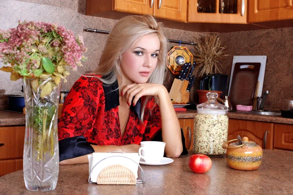 Kvinna frukost med äpple och kopp varm dryck i köket — Stockfoto