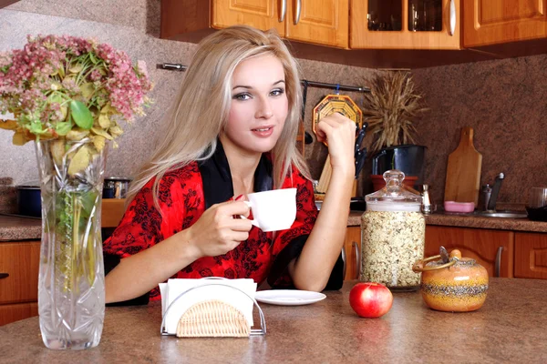 Mujer desayuno con manzana y taza de bebida caliente en la cocina — Foto de Stock