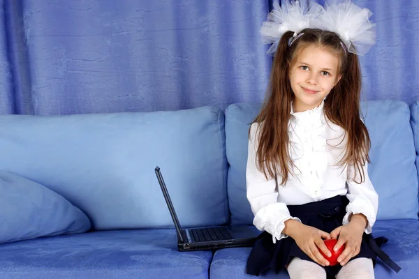 Schoolgirl with laptop and red apple in sofa — Stock Photo, Image