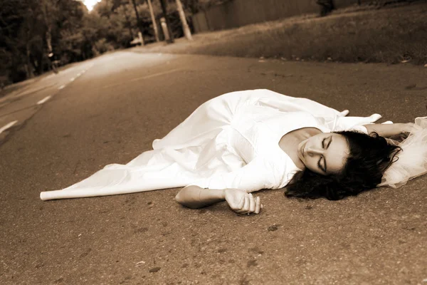 Noiva deitada na estrada — Fotografia de Stock
