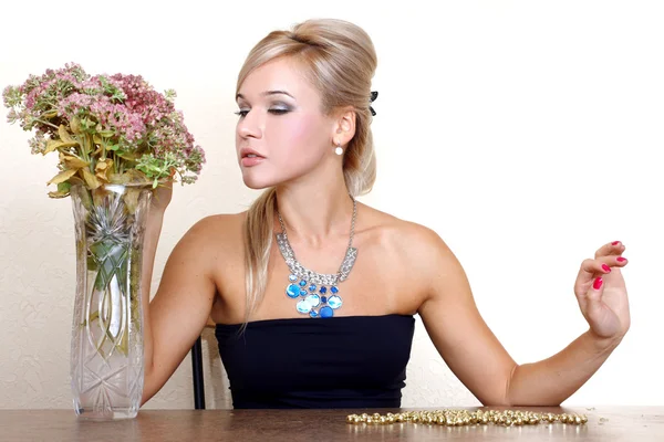 Kvinna som tittar en höst blommor mot gul vägg på tabell — Stockfoto