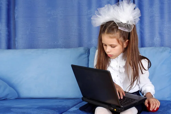 Těžký den v učení - dívka s laptop a červené jablko v pohovce — Stock fotografie