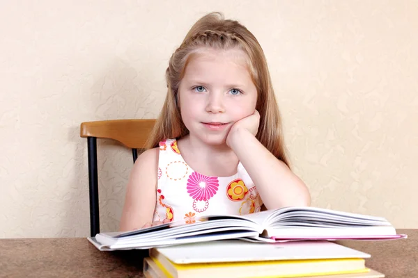 Little girl reading book in the kitchen against yellow wall at h — Stock Photo, Image
