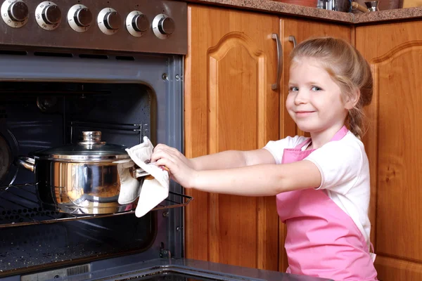 Klein meisje genomen het voedsel uit de keuken oven — Stockfoto