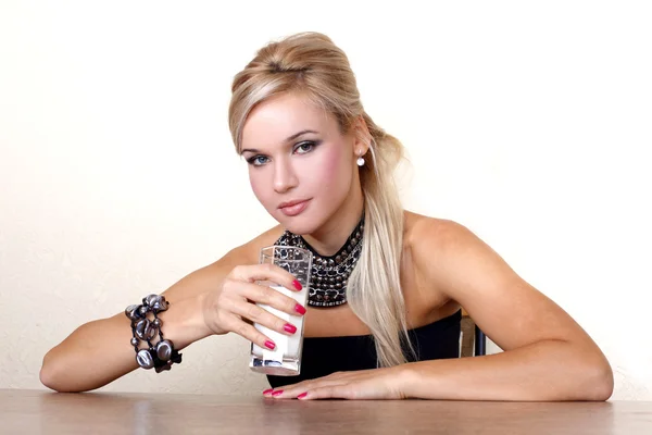 Vrouw met glas melk tegen gele muur aan tafel — Stockfoto