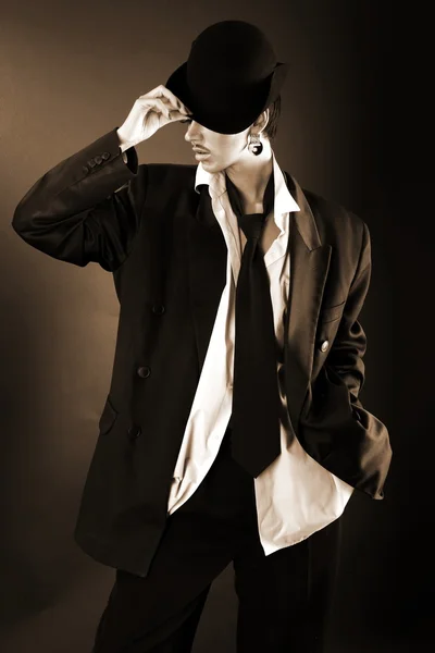 Νέος μόδα μοντέλο στο καπέλο, πουκάμισο μεγάλε και παλτό ενάντια μαύρο — Φωτογραφία Αρχείου