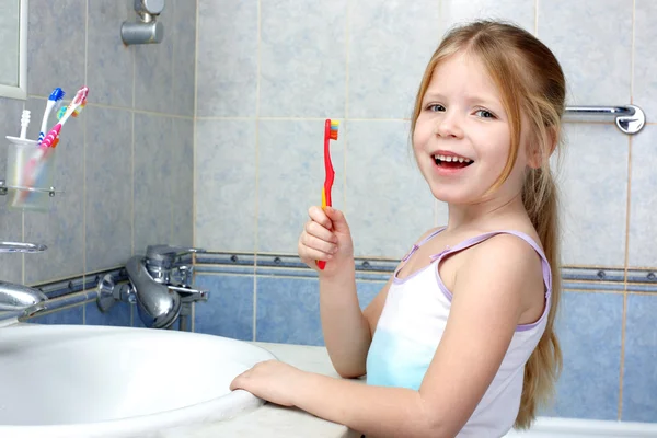 Маленькая девочка с зубной щеткой в ванной — стоковое фото