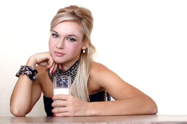 Donna con bicchiere di latte contro parete gialla a tavola — Foto Stock