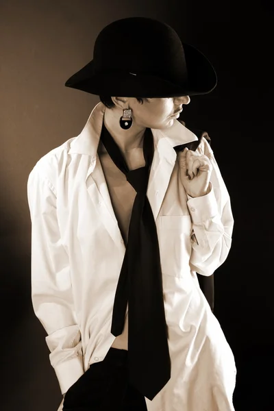 Giovane modella in cappello, camicia uomo grande contro nero — Foto Stock