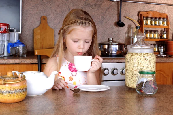 Kleines Mädchen frühstückt und bläst zur Tasse Heißgetränk in den Kit — Stockfoto