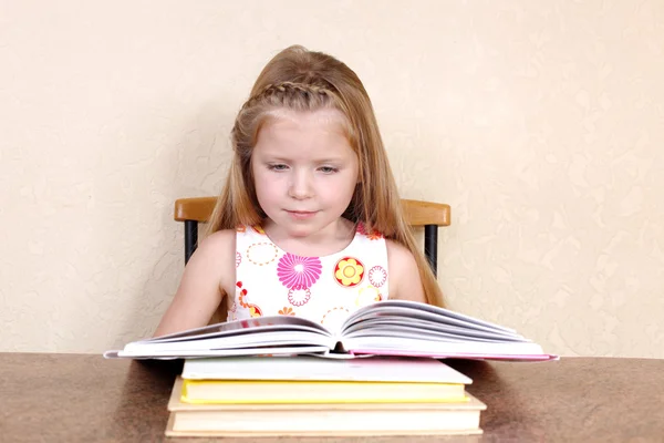 Klein meisje leesboek in de keuken tegen gele muur bij h — Stockfoto